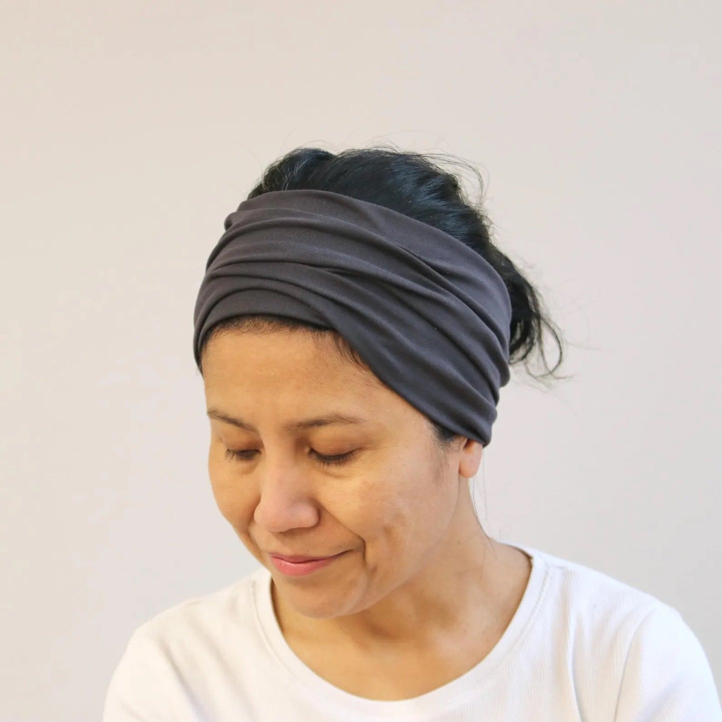 Woman wearing a gray headband against a plain background