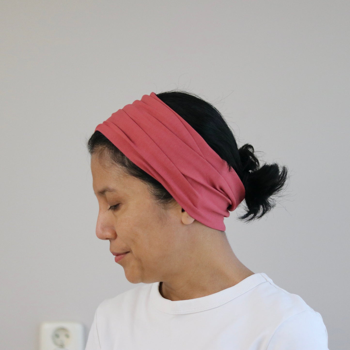 Person wearing a pink headband against a plain background