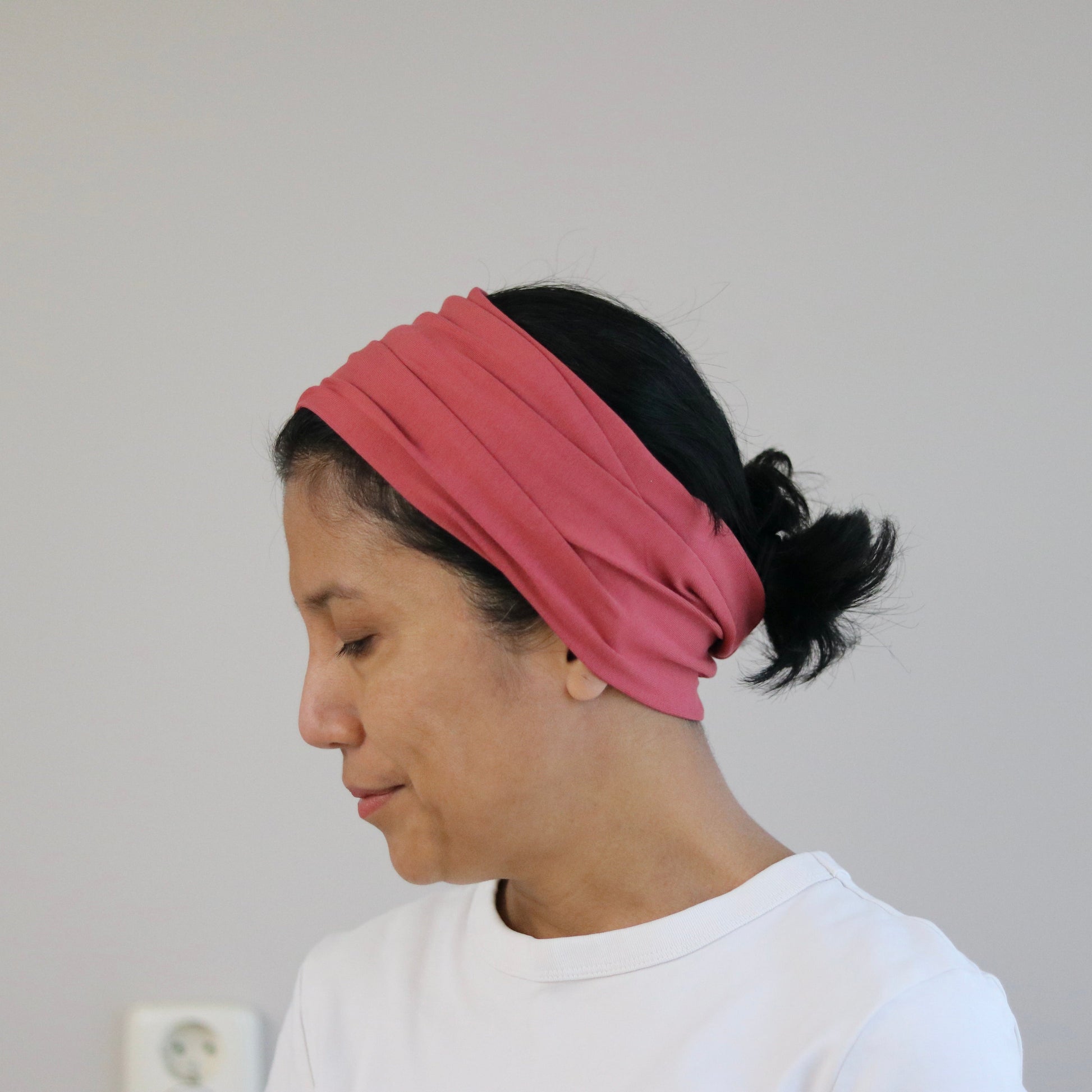 Person wearing a pink headband against a plain background