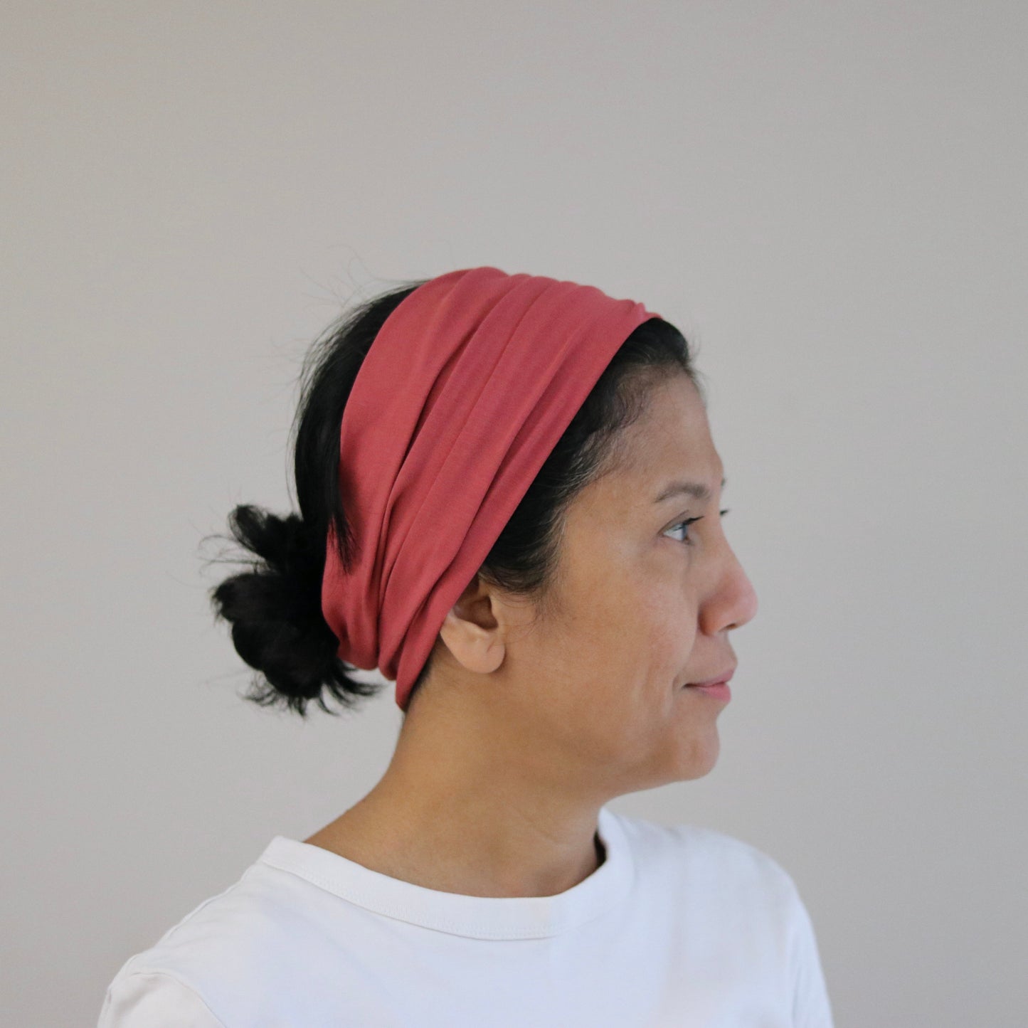 Woman wearing a pink headband against a plain background