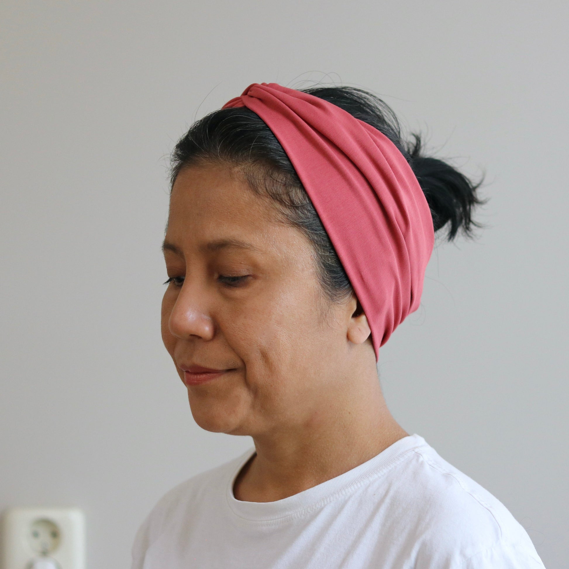 Woman wearing a pink headband against a plain background