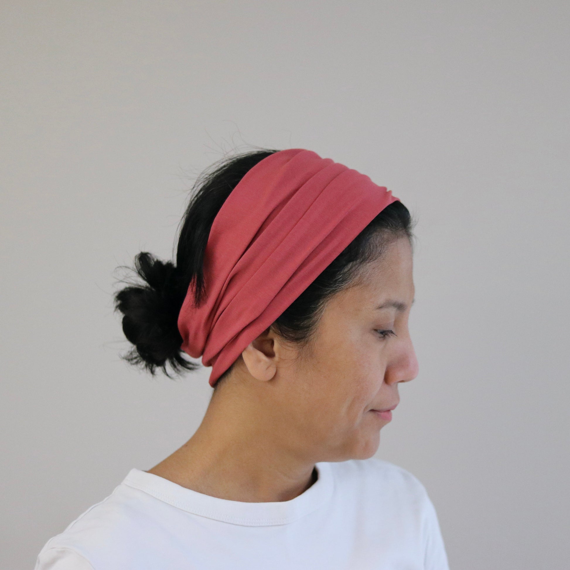 Woman wearing a pink headband against a plain background