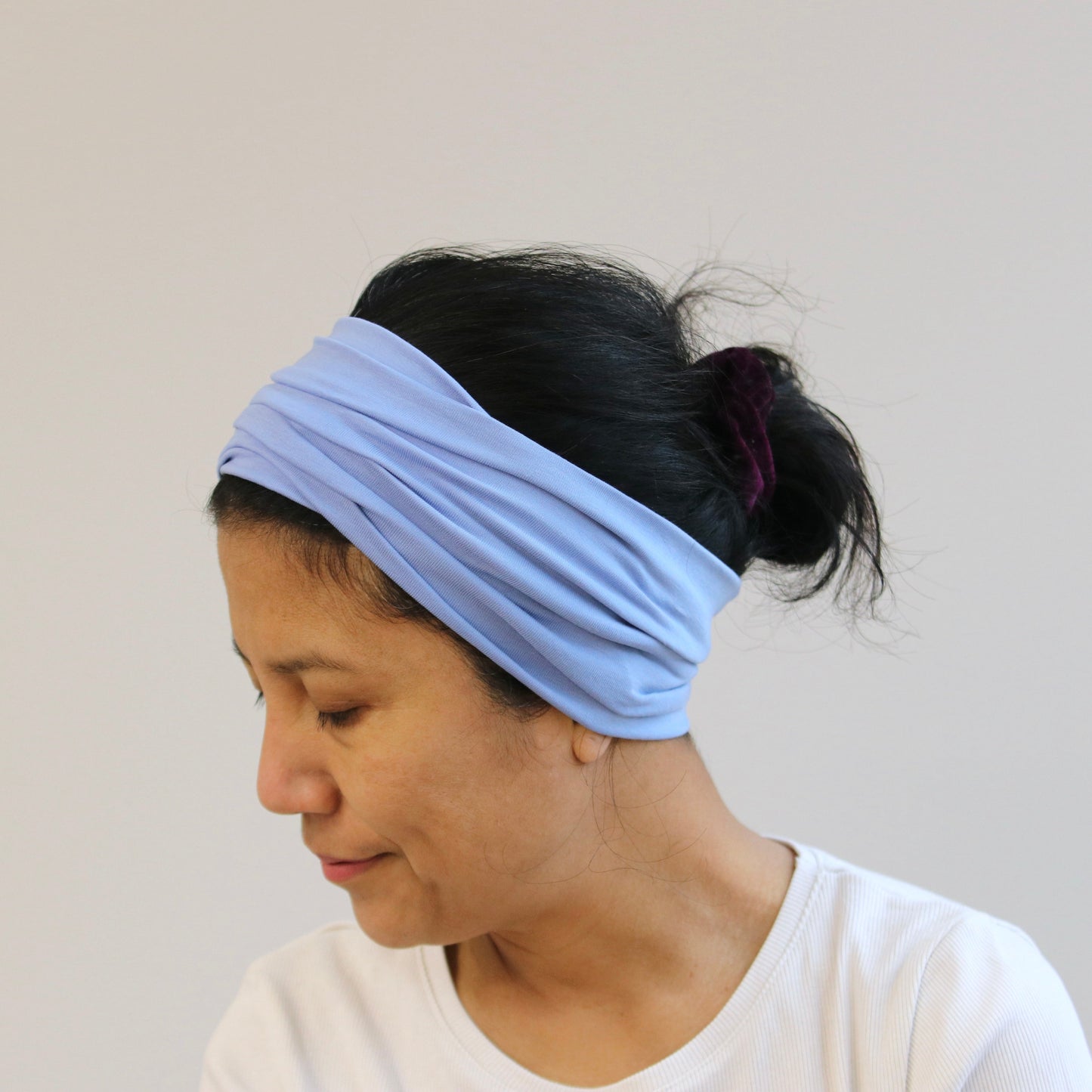 Woman wearing a light blue headband against a plain background