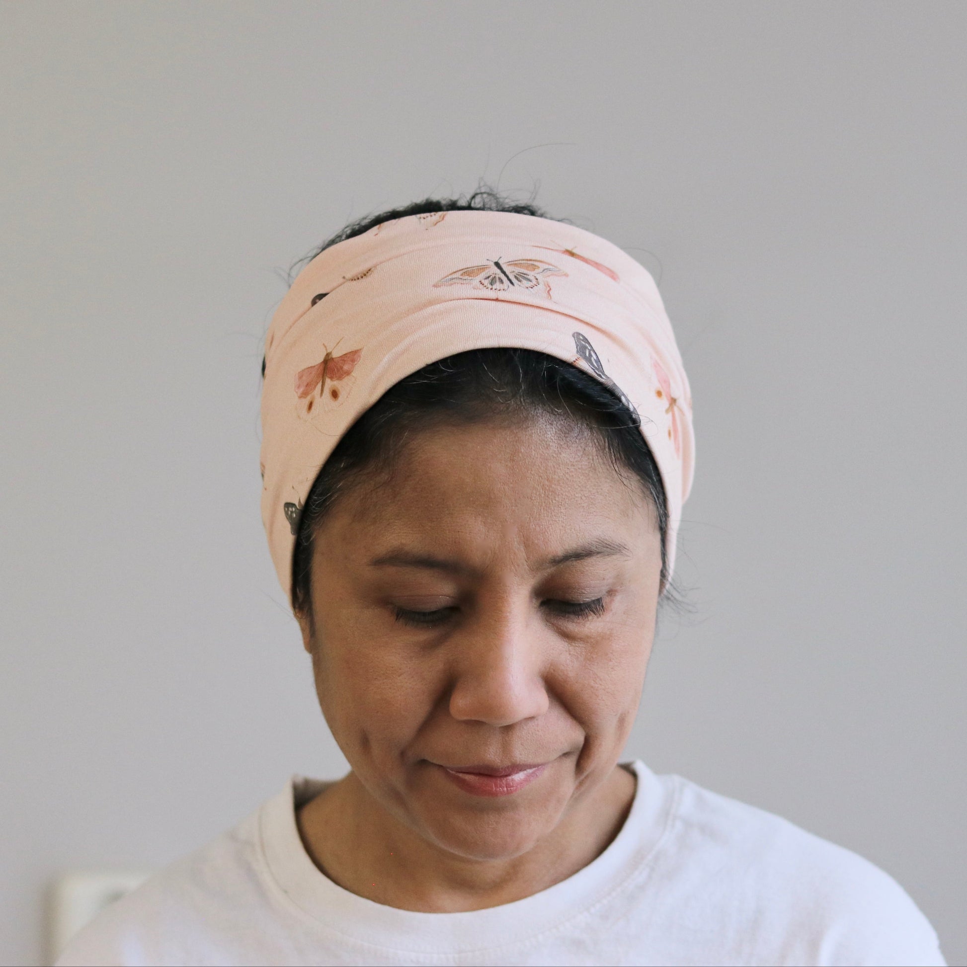 Woman wearing a patterned headband against a plain background