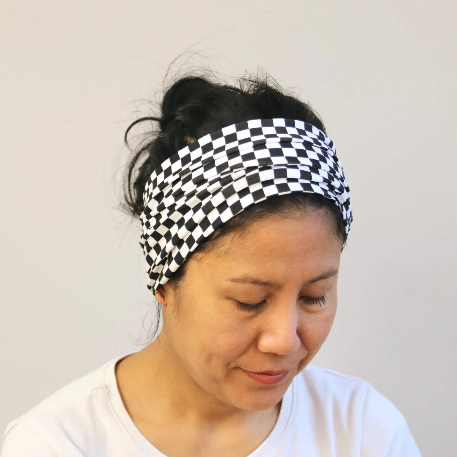 Person wearing a black and white checkered headband against a plain background