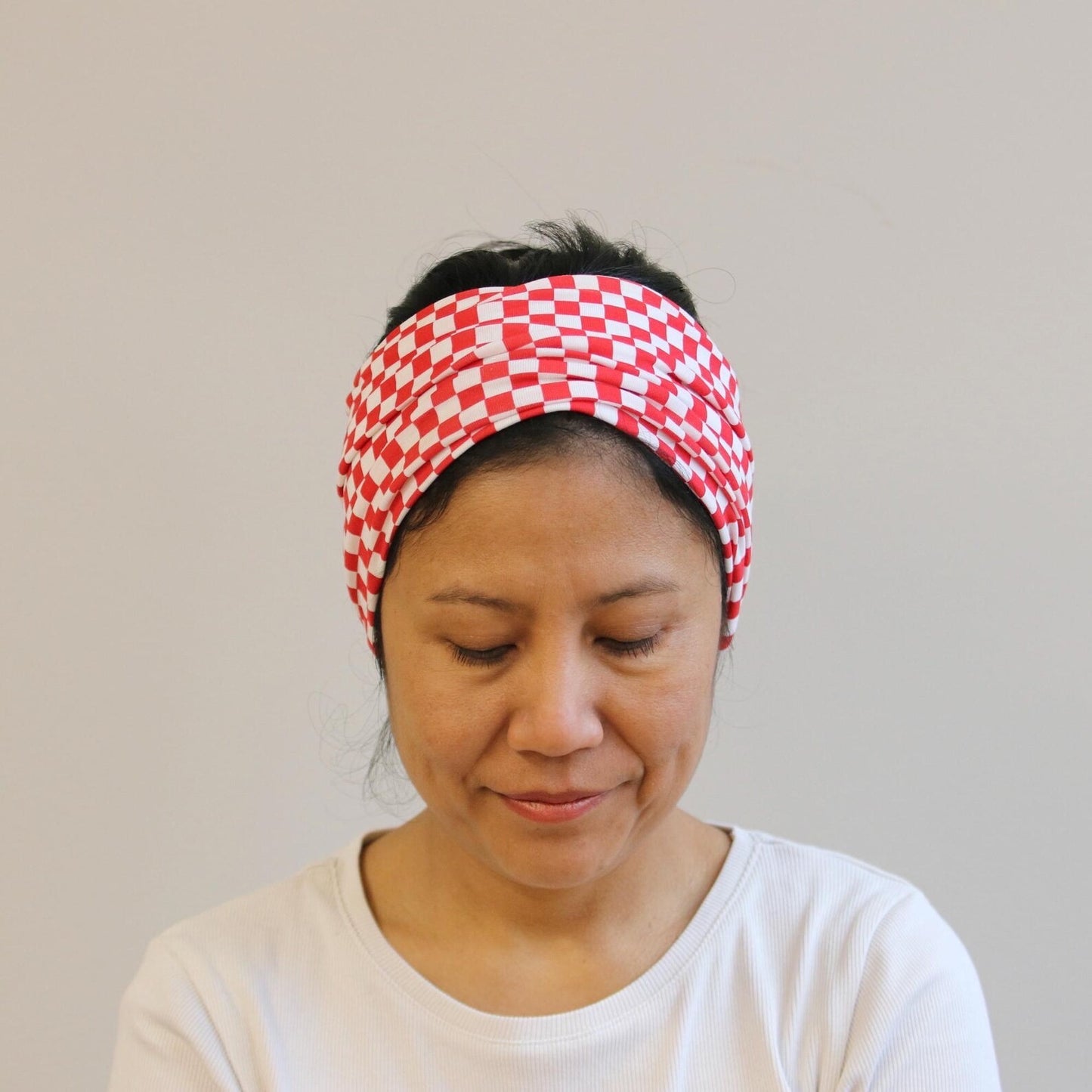 Person wearing a red and white checkered headband against a plain background
