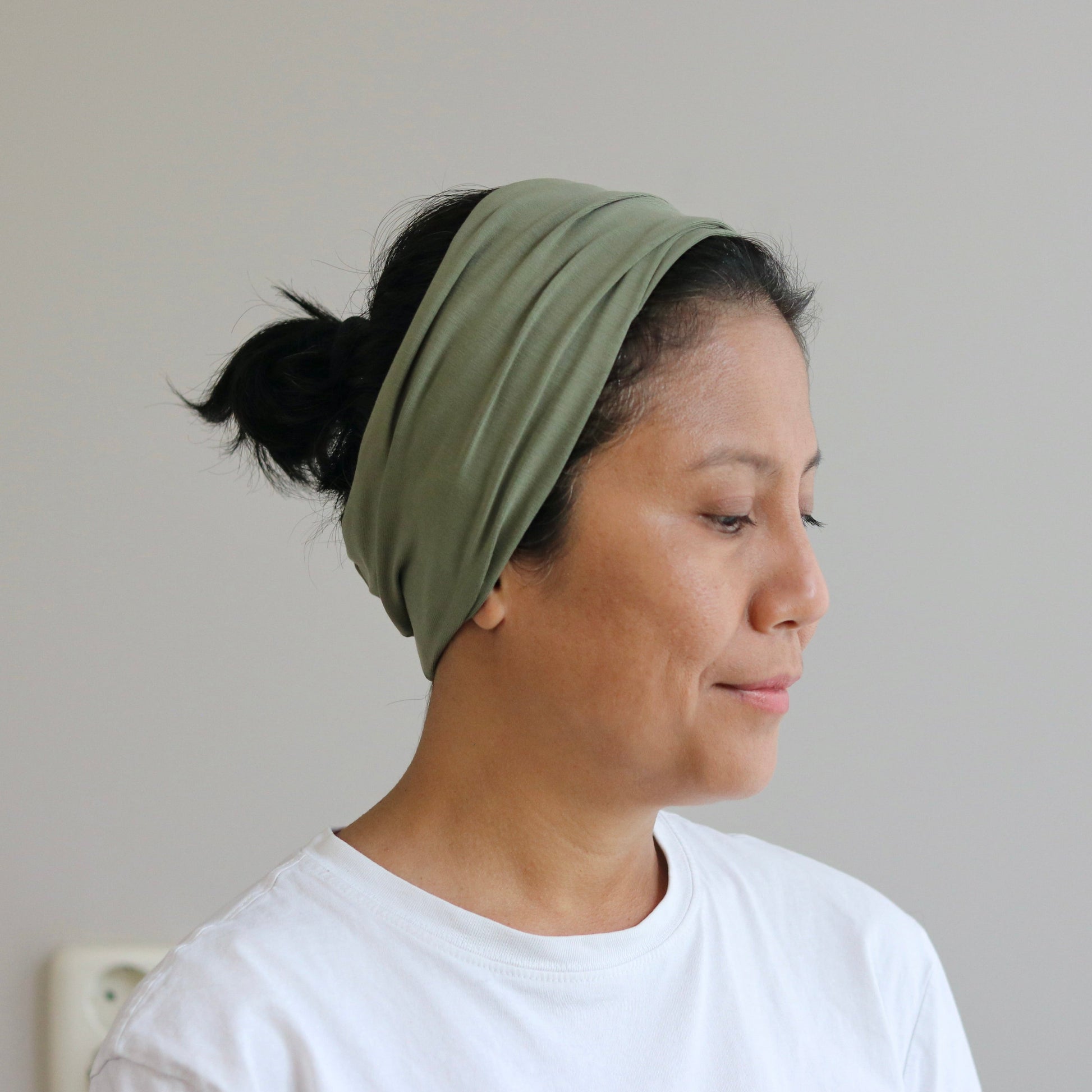 Woman wearing a green headband against a plain background