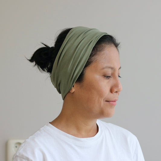 Woman wearing a green headband against a plain background
