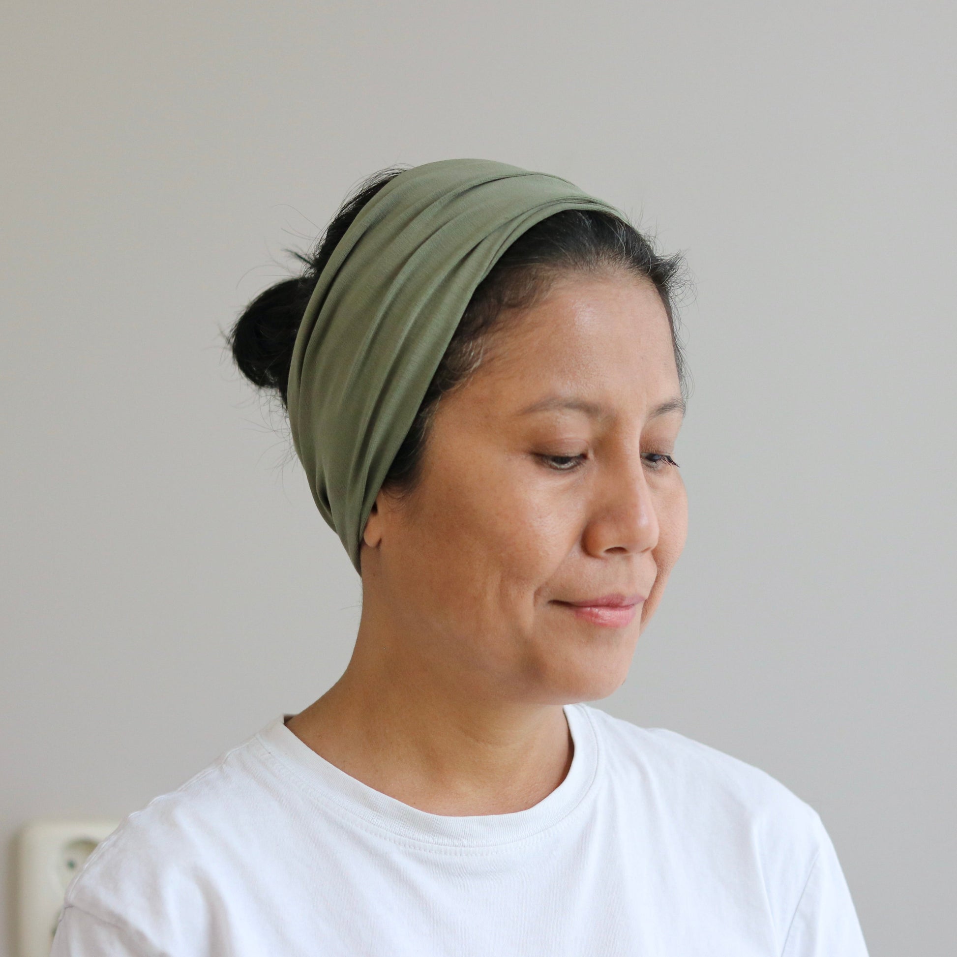 Woman wearing a green headscarf against a plain background