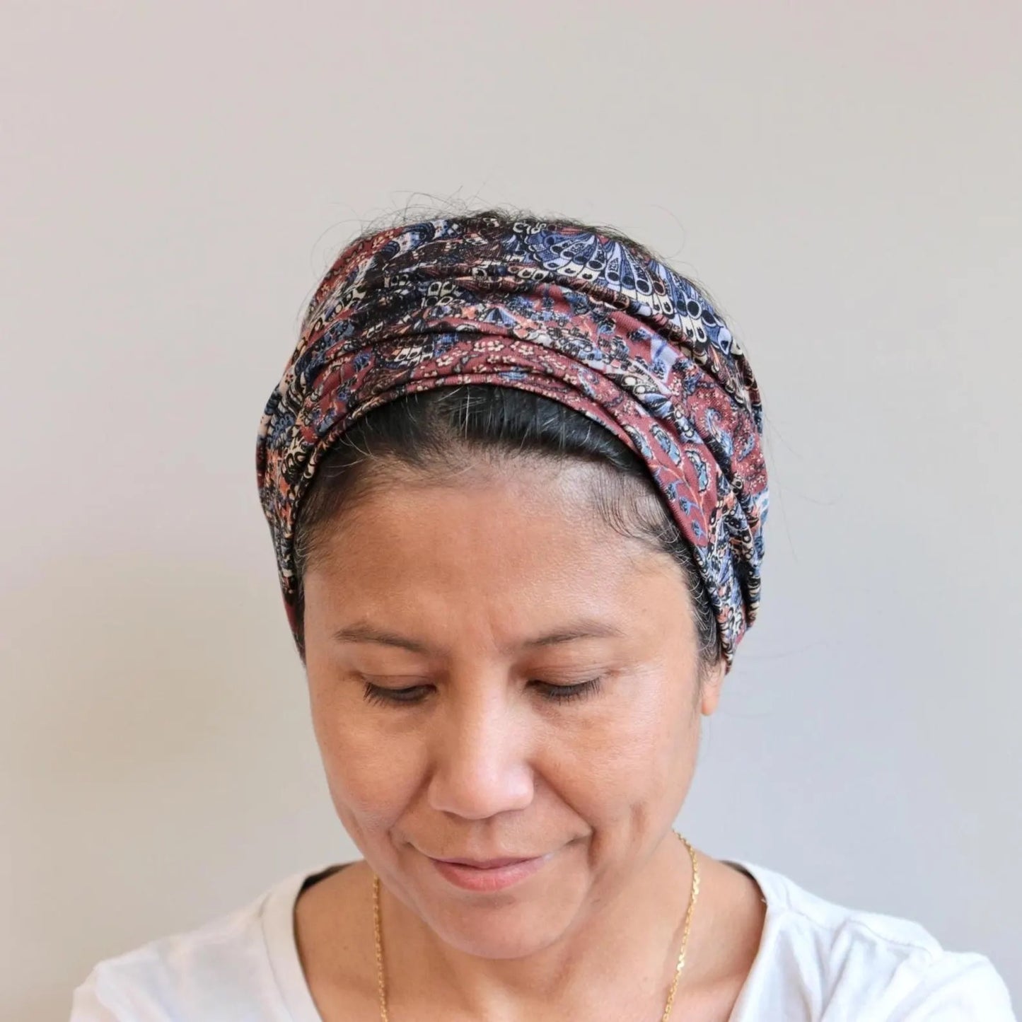 Woman wearing a patterned headscarf against a plain background