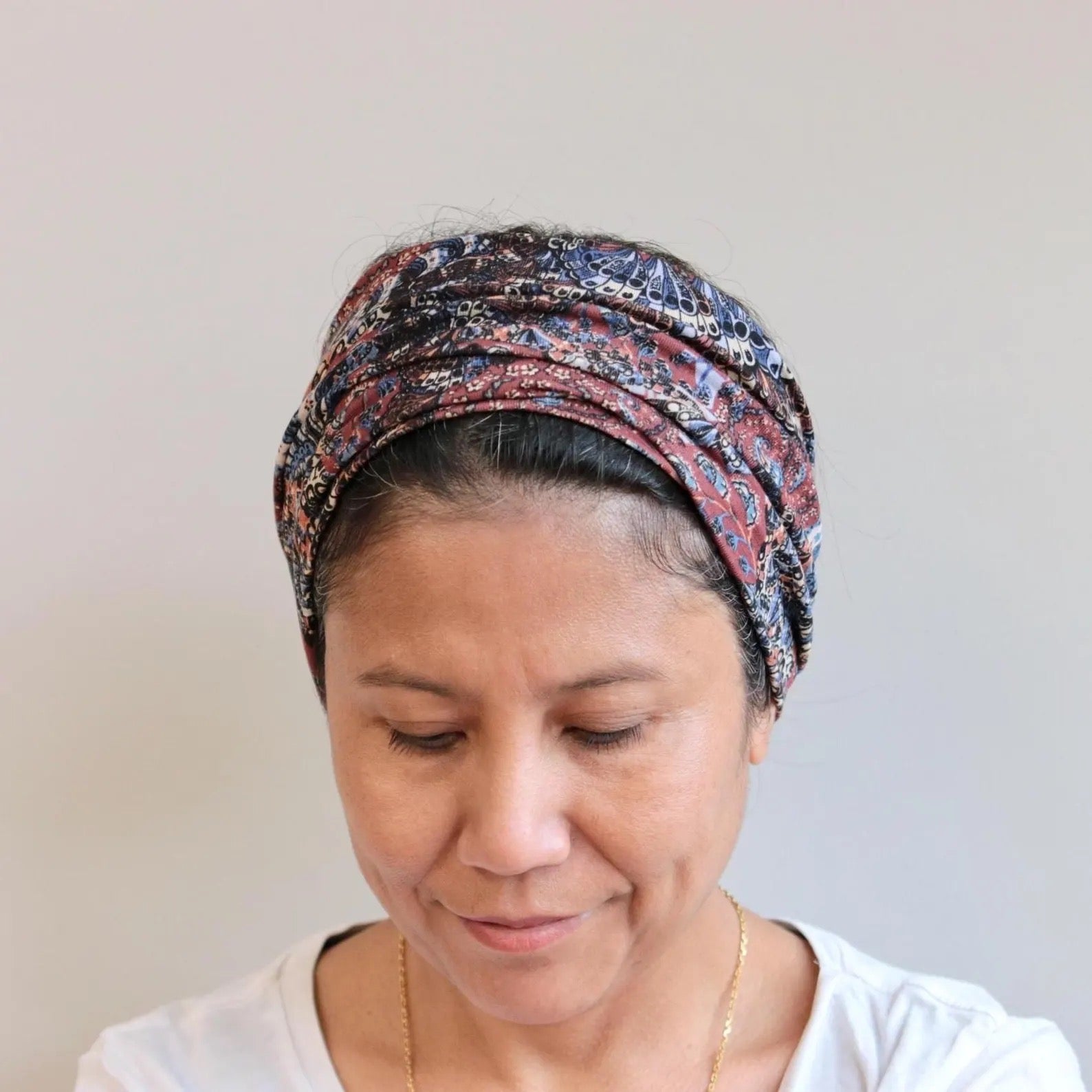 Woman wearing a patterned headscarf against a plain background