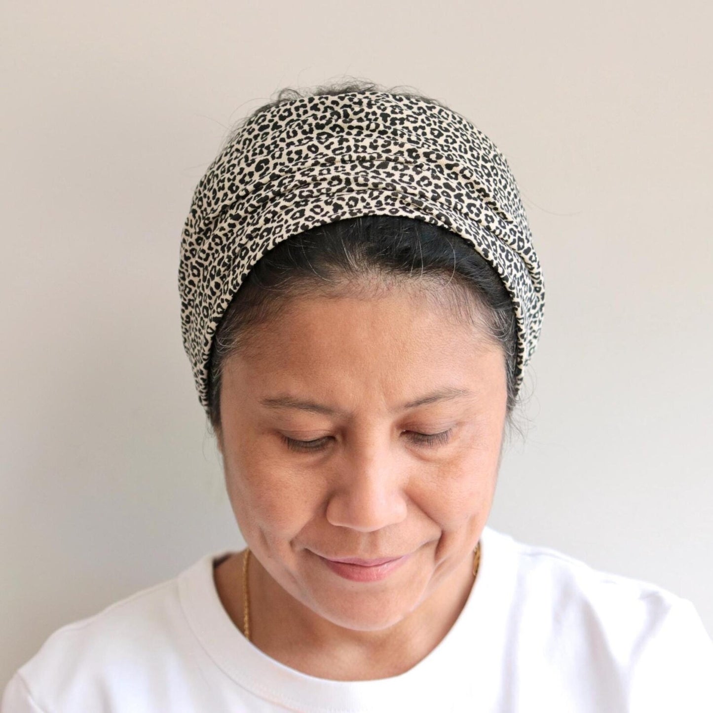 Woman wearing a leopard print headband against a plain background