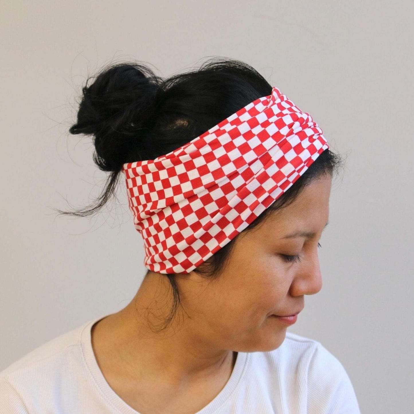 Person wearing a red and white checkered headband against a plain background