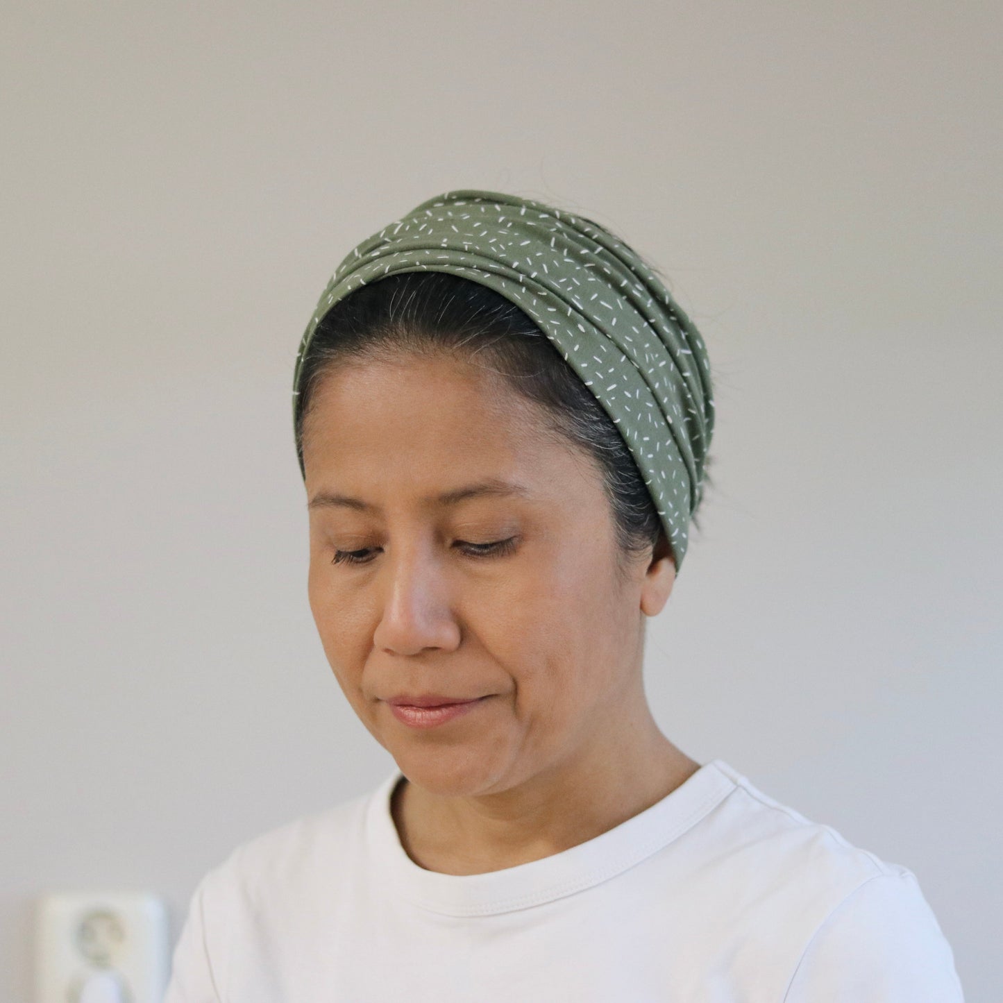 Woman wearing a green headscarf against a plain background