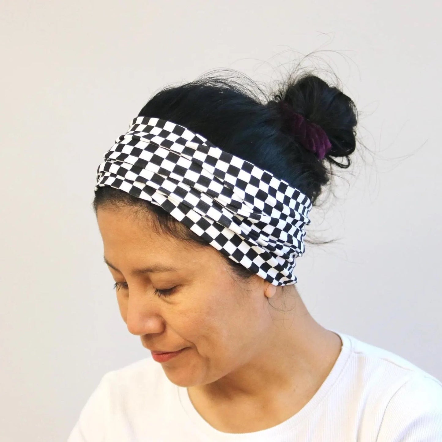 Person wearing a black and white checkered headband against a plain background