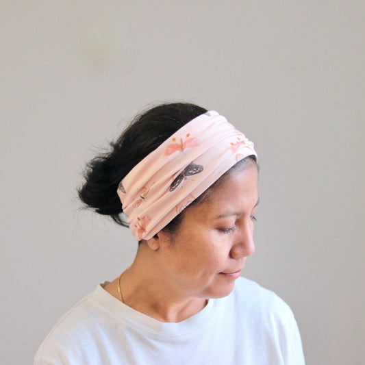 Woman wearing a pink floral headband against a plain background