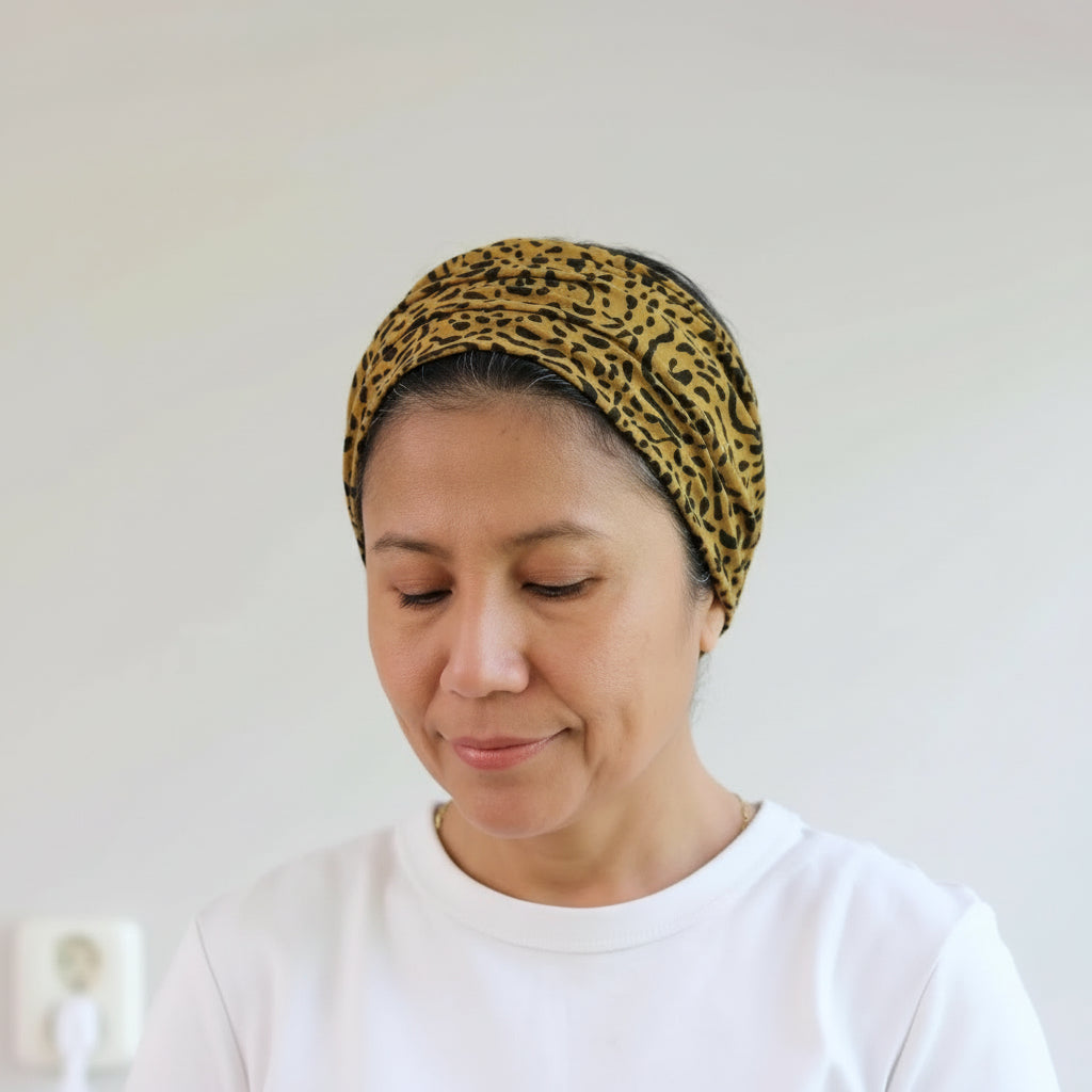 Woman wearing a leopard print headscarf against a plain background