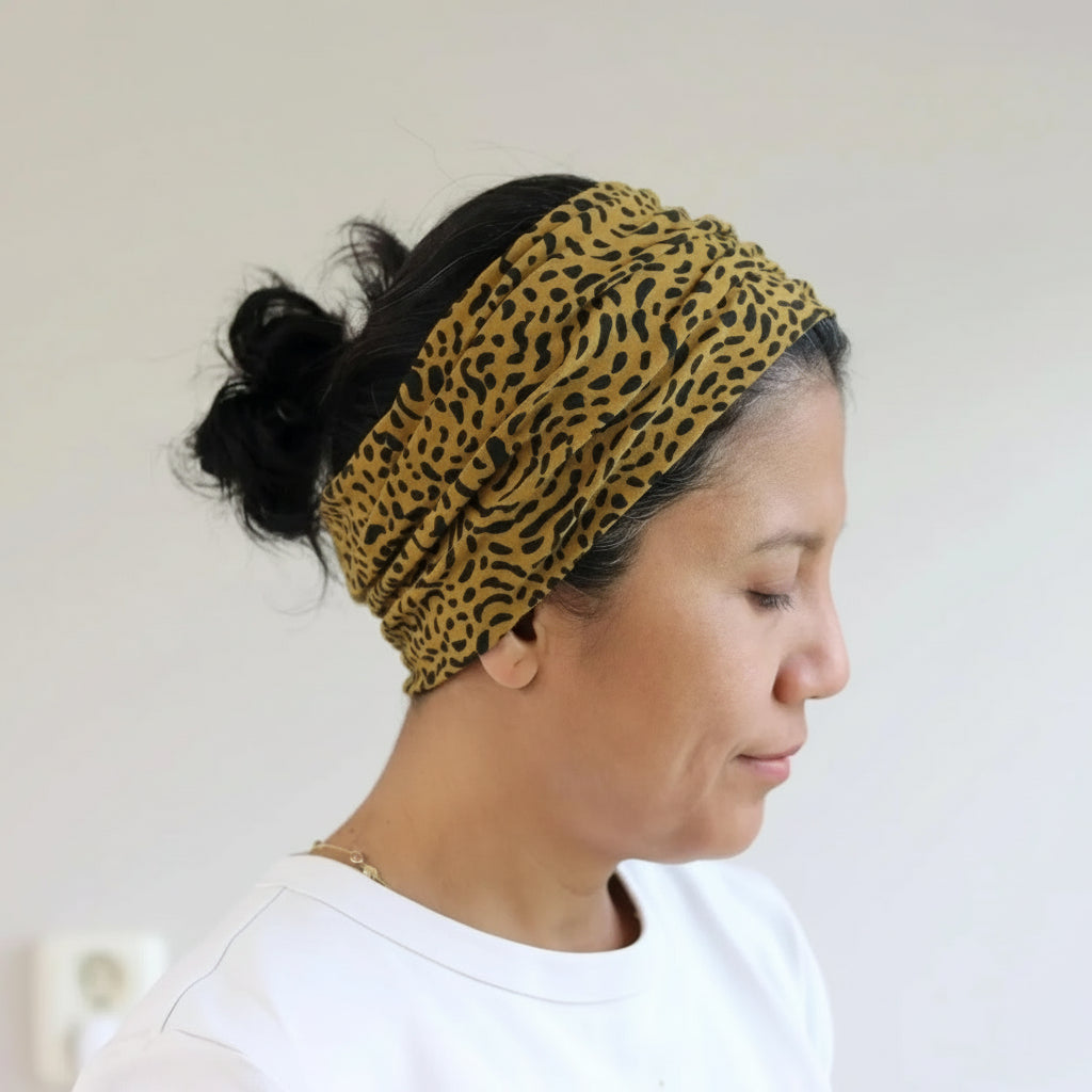 Person wearing a leopard print headband against a plain background