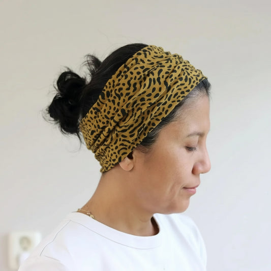 Person wearing a leopard print headband against a plain background