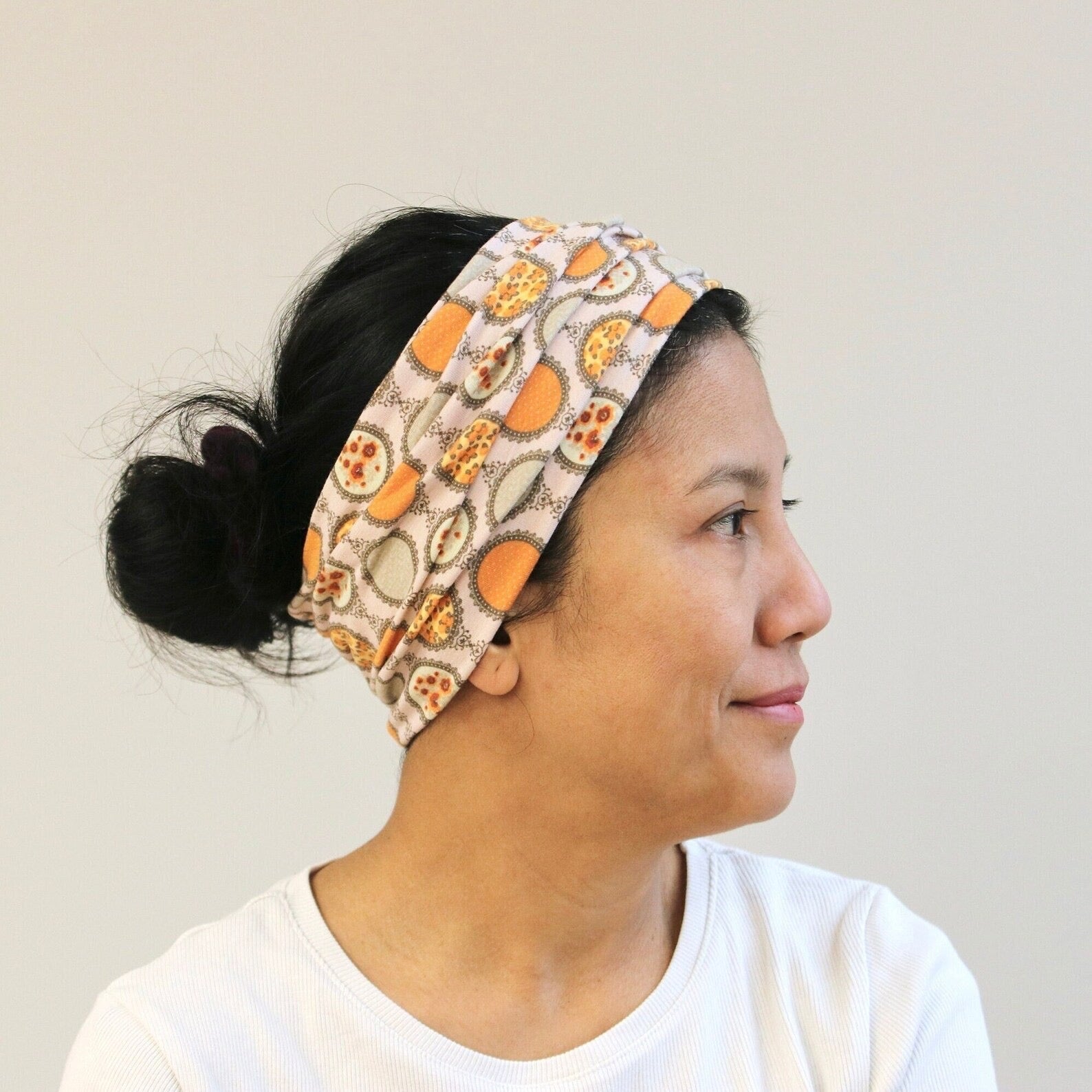 Woman wearing a patterned headband with pumpkins and leaves on a plain background