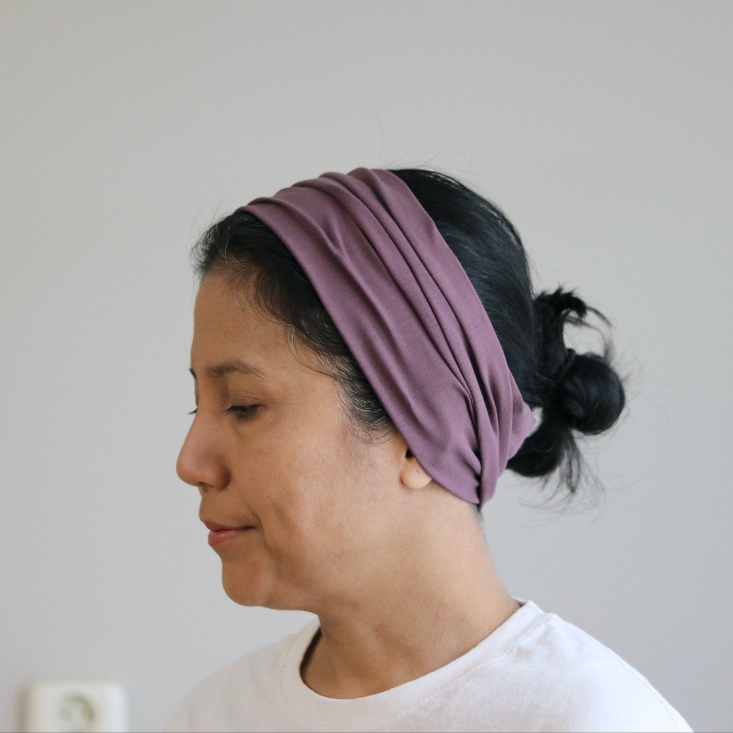 Woman wearing a purple headband against a plain background