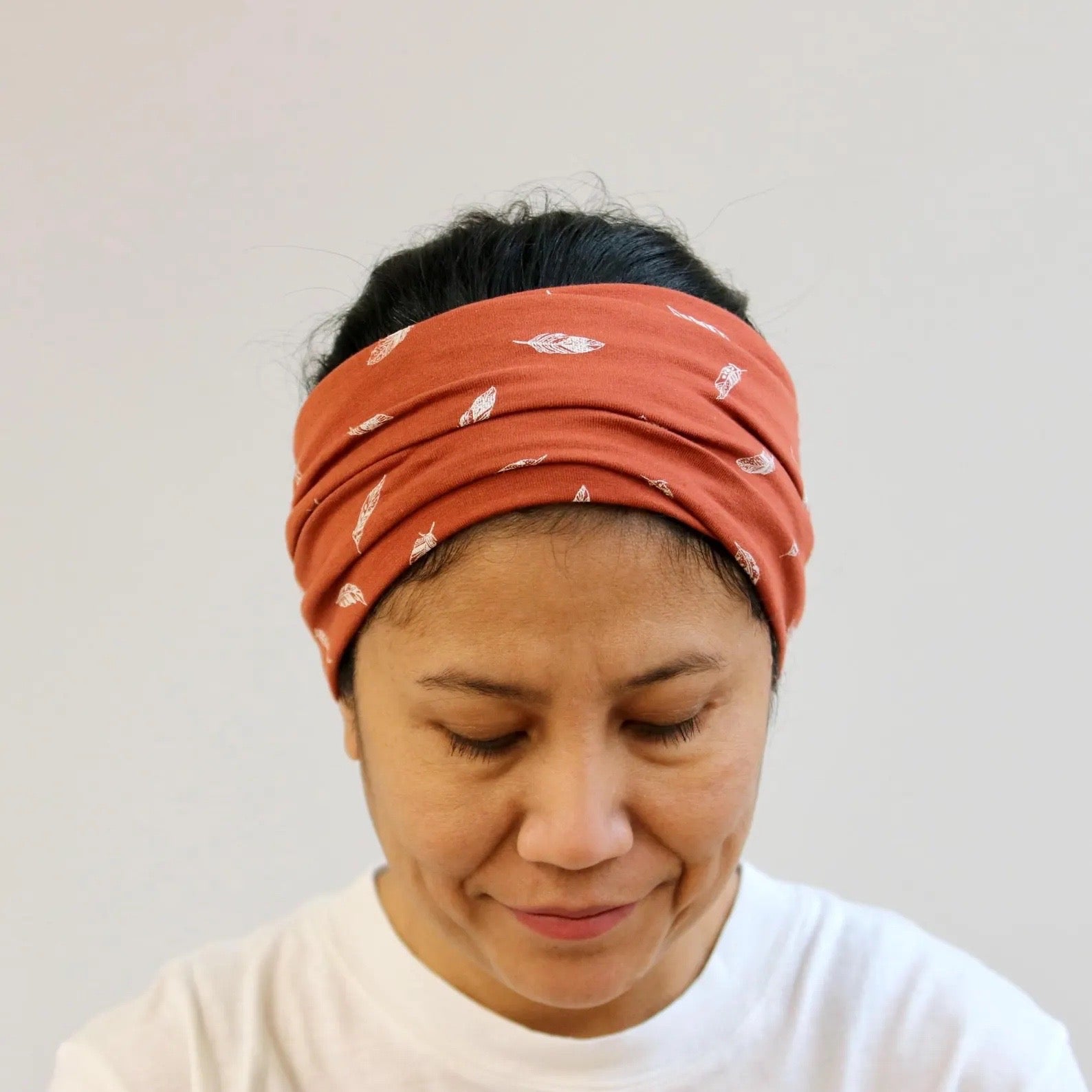 Person wearing a rust-colored headband with white patterns on a plain background
