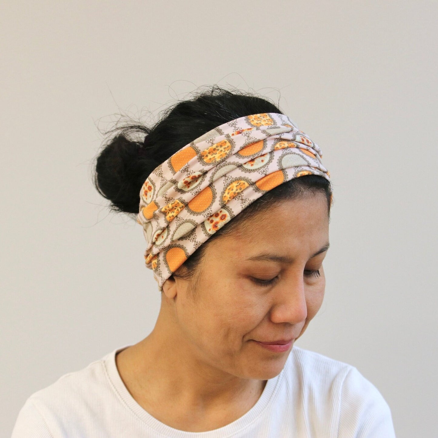 Woman wearing a patterned headband against a plain background