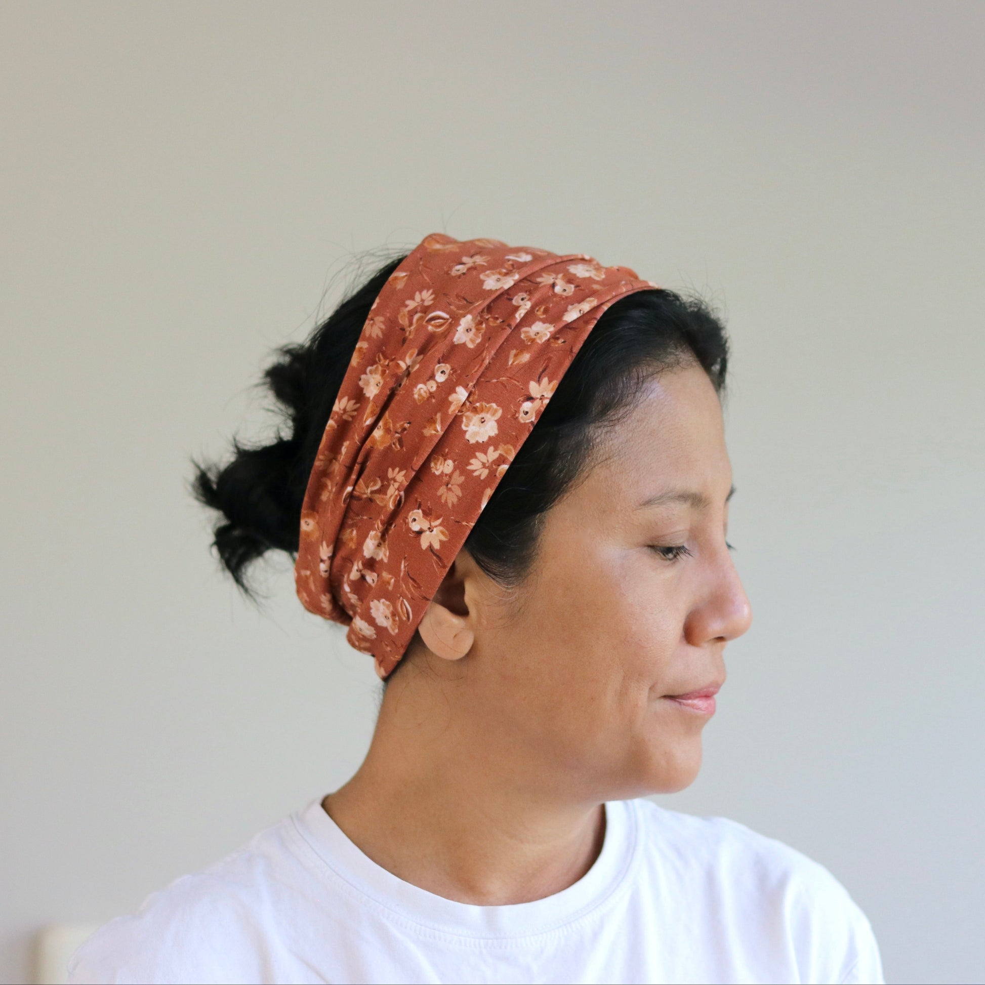 Woman wearing a patterned headscarf against a plain background