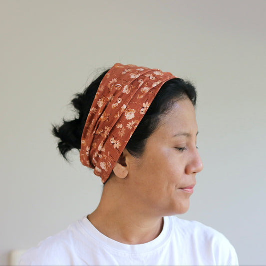 Woman wearing a patterned headscarf against a plain background