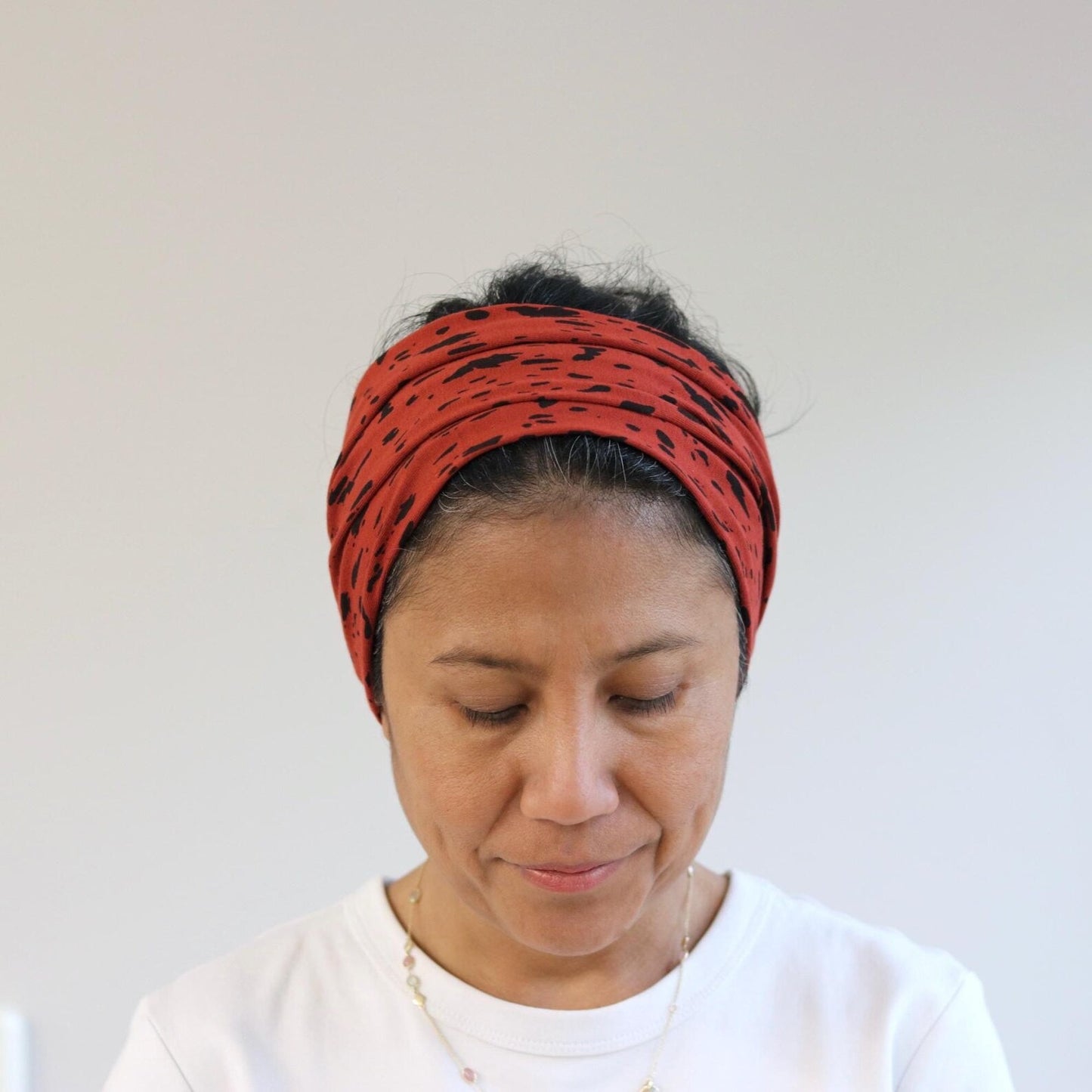 Woman wearing a red patterned headband against a plain background
