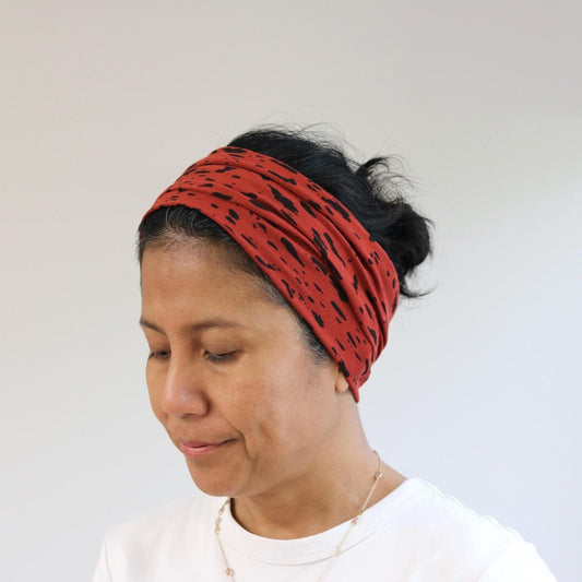 Woman wearing a red patterned headband against a plain background