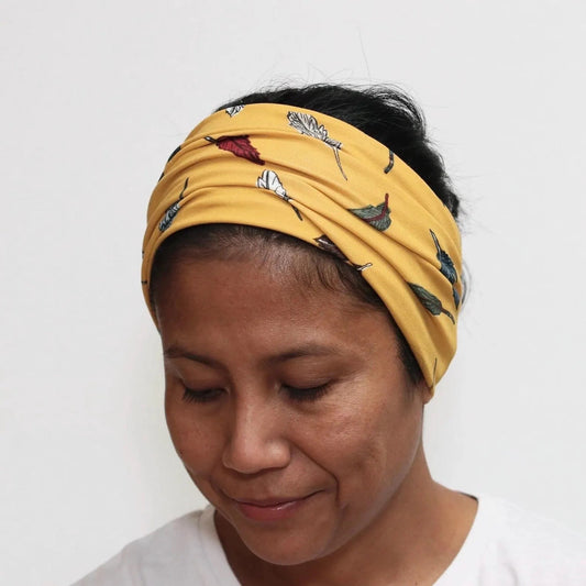 Person wearing a yellow headband with feather pattern on a white background
