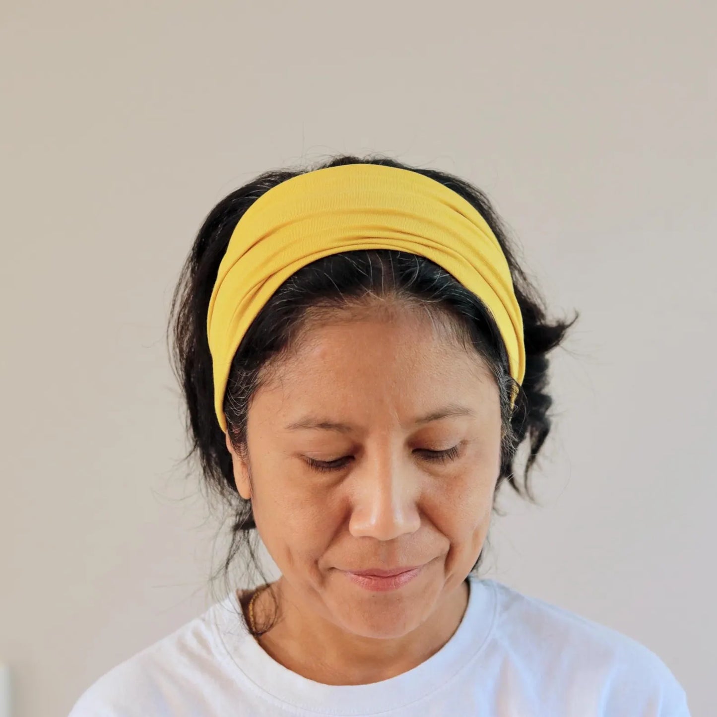 Woman wearing a yellow headband against a plain background