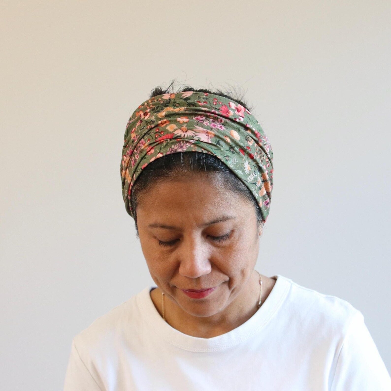 Woman wearing a patterned headscarf against a plain background