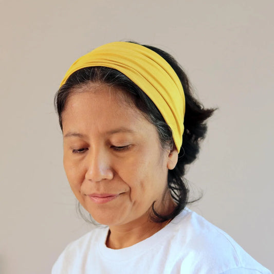 Woman wearing a yellow bamboo headband against a plain background